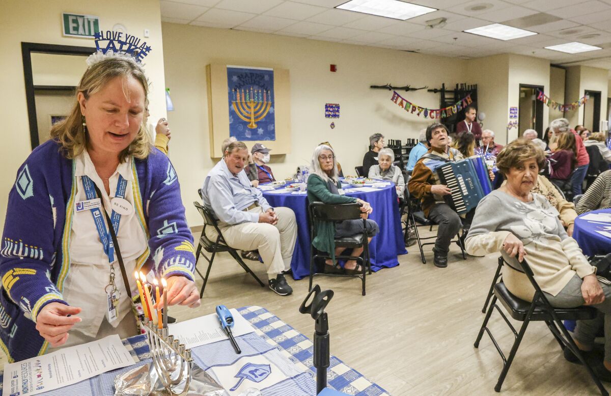 a woman lights a menorah during a luncheon