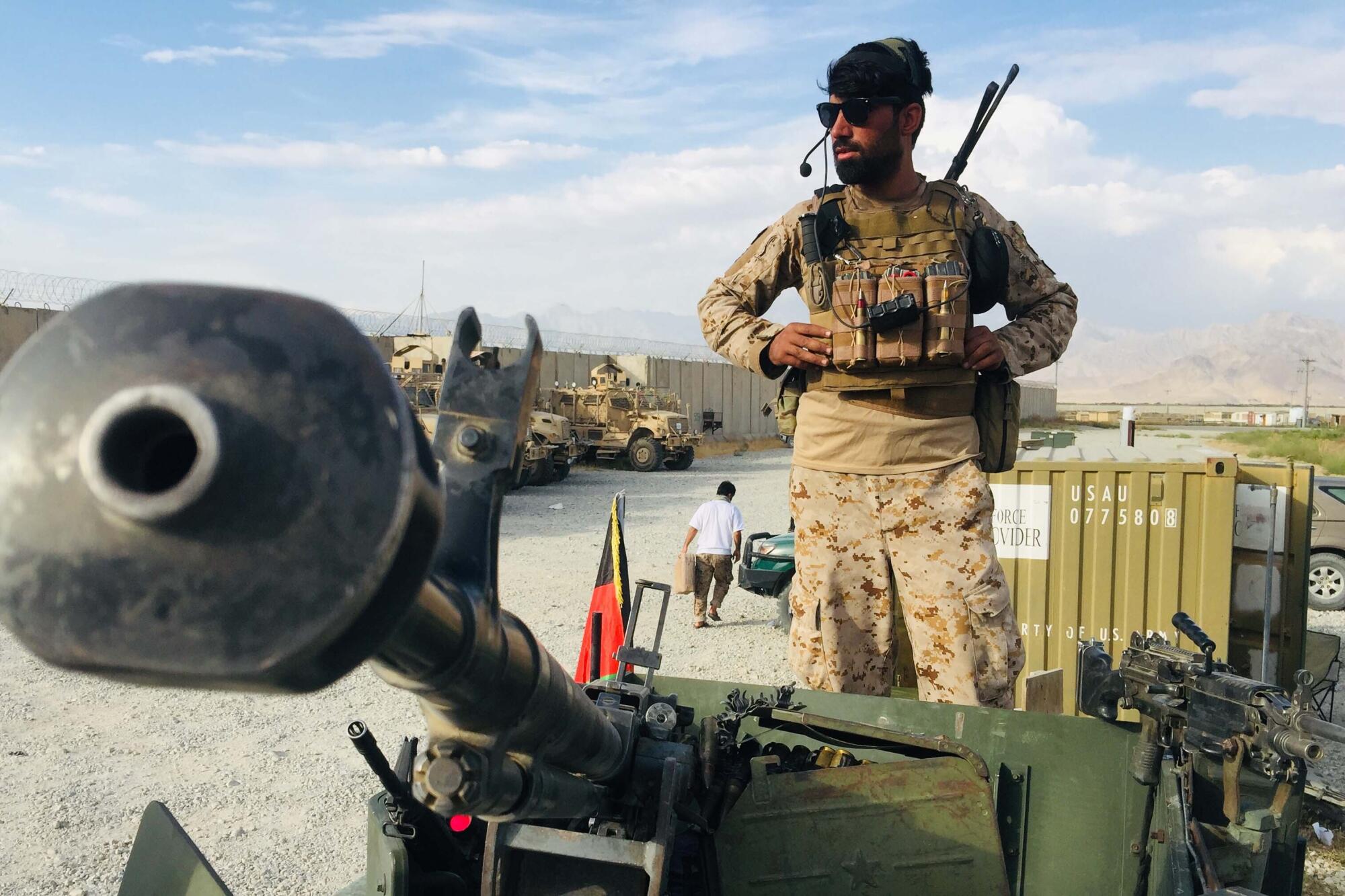 An Afghan soldier stands on a vehicle.