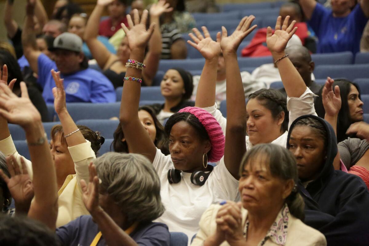 Tracy Willis, wearing a cap, and others raise their hands in support of a blue ribbon commission's recommendations to overhaul the way Los Angeles County delivers child protection services.