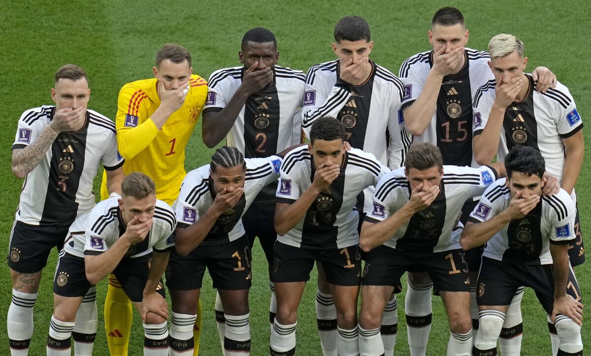 German soccer players cover their mouths as they pose for a group photo before their World Cup match 