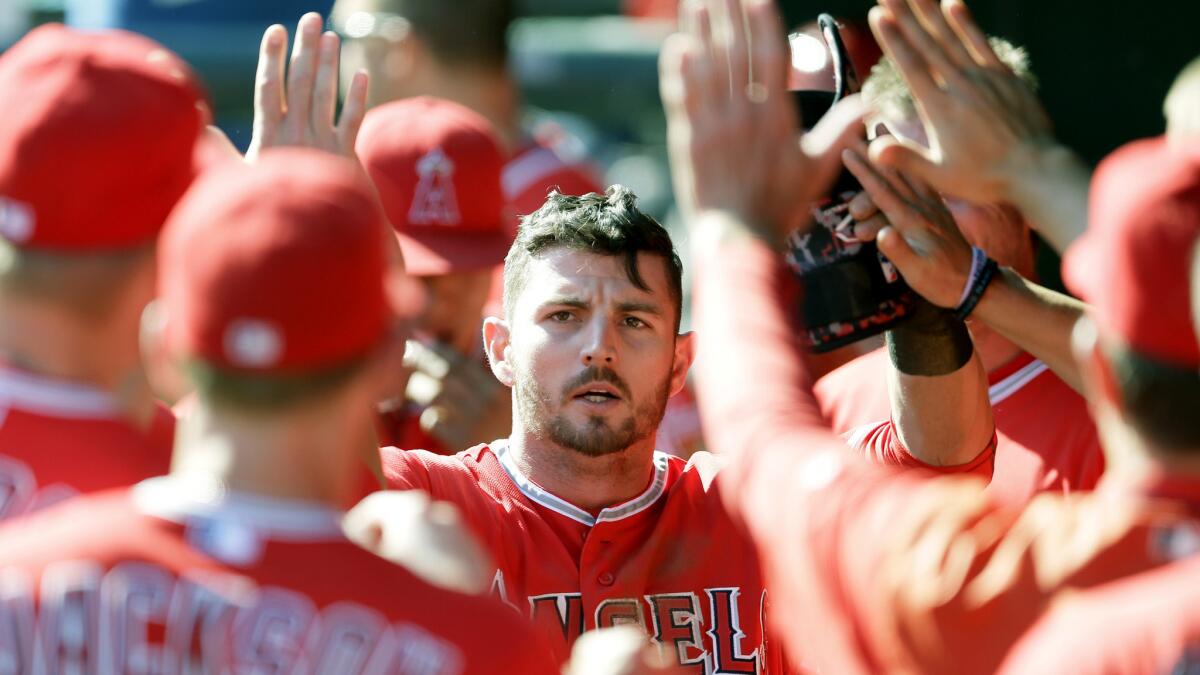 Angels second baseman Johnny Giavotella is congratulated in the dugout by teammates after he drove in the go-ahead run against the Rangers in the five-run ninth inning Saturday afternoon.