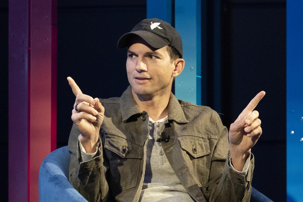 A man in a baseball cap points his fingers in different directions.