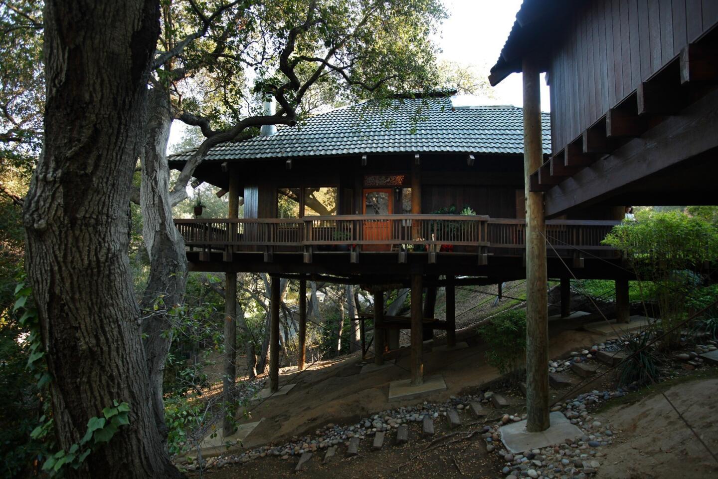 The Reeds' house is supported by 10 ponderosa pine poles, a kit of parts based on a Japanese building technique from the 16th century. A deck wraps the window-lined residence; a detached garage sits in the foreground.