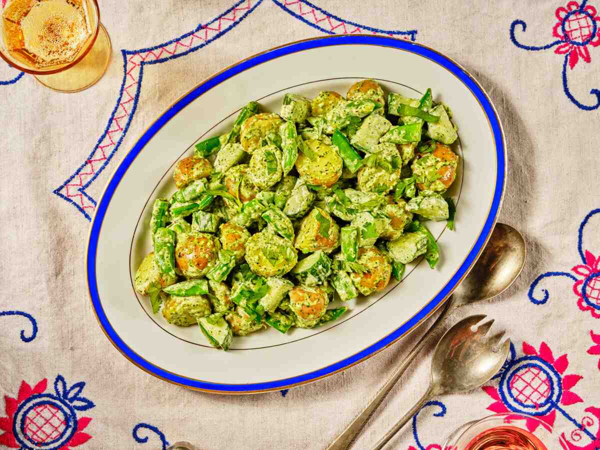 Overhead view of a plate with a salad that includes chunks of potato, snap peas and cucumbers.