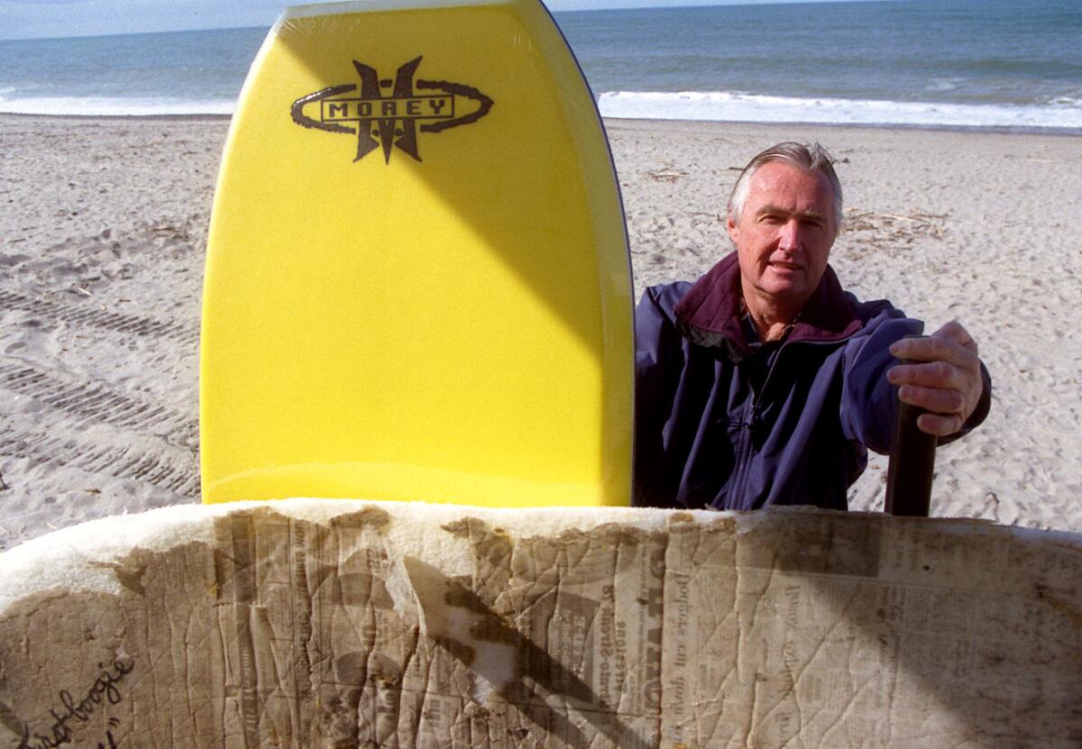 Tom Morey photographed with his original 1971 Boogie Board in front and a more recent model (yellow).