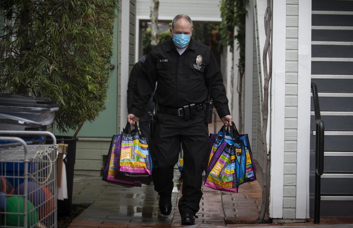 LAPD Officer Kirk Barnes carries bags of food on Thursday while making deliveries to Hollywood seniors.