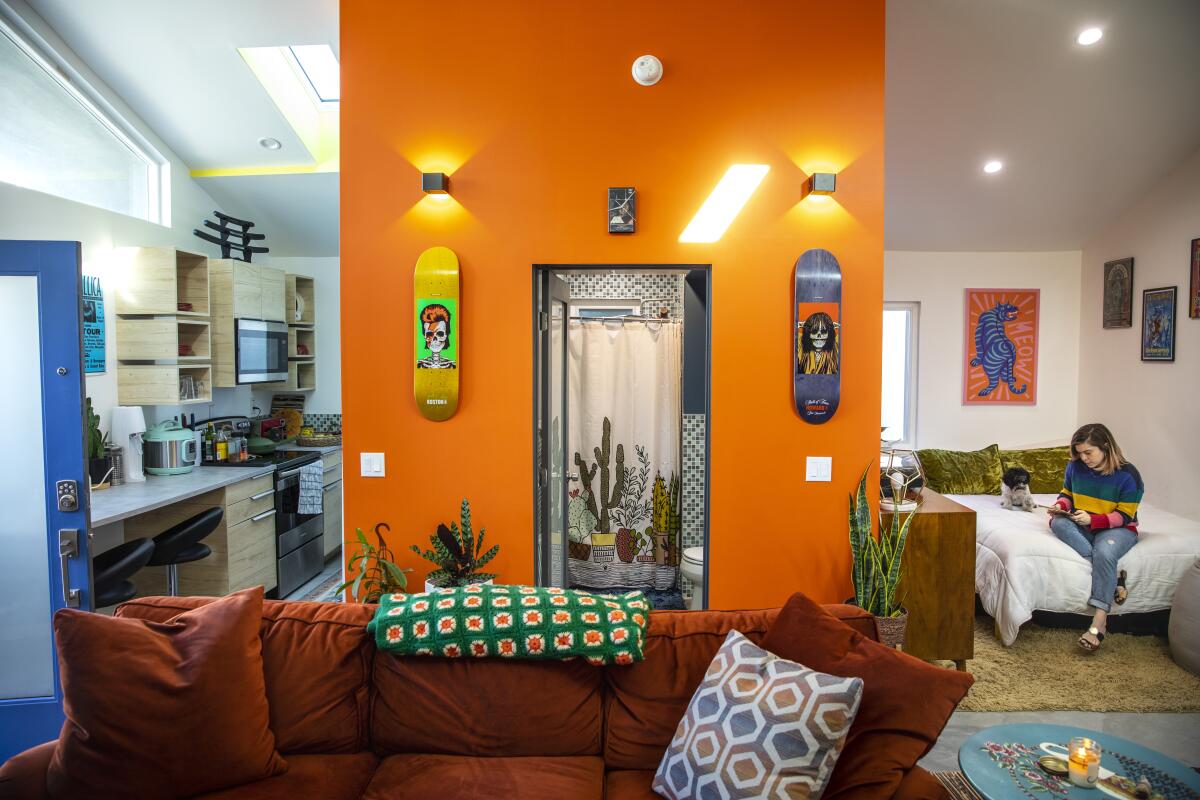 A view of Casita L.A. shows a small galley kitchen, a bathroom, a sleeping area and a wall accented in orange