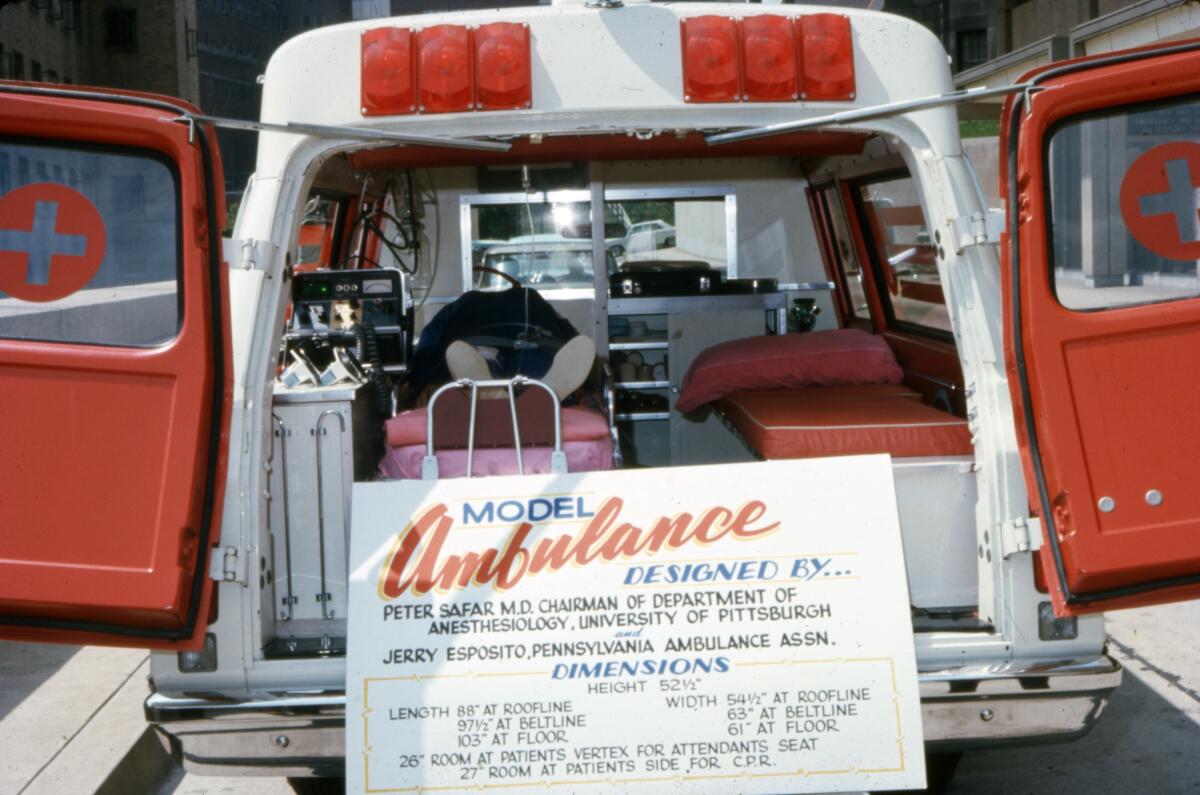 A model ambulance with its rear doors open and a sign describing its design