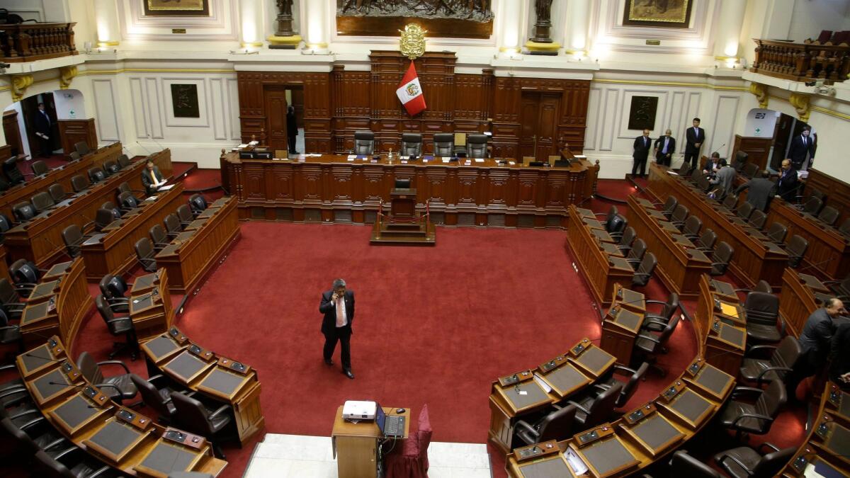 A congressman paces the empty congressional chamber in Lima, Peru, as he waits the start of a vote on whether to initiate impeachment proceeding against President Pedro Pablo Kuczynski.