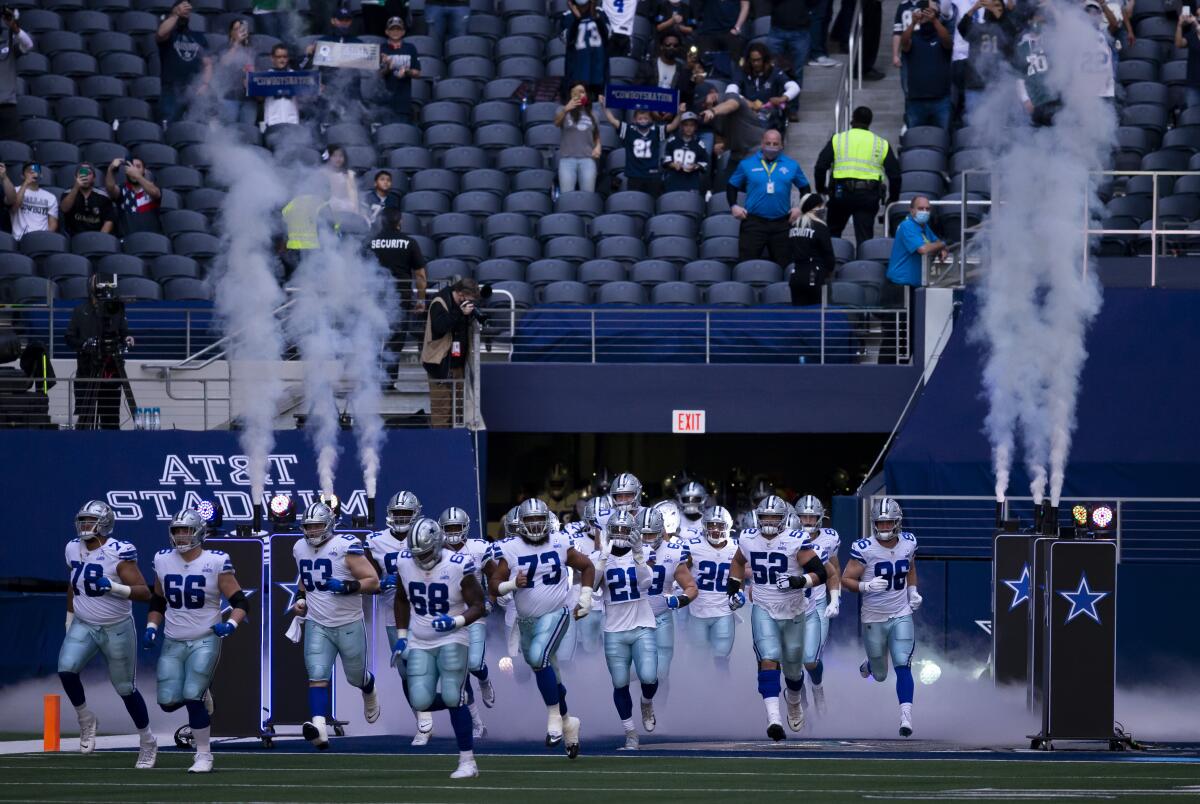 Dallas Cowboys players run onto the field at AT&T Stadium in Arlington, Texas, before a game against the Philadelphia Eagles.
