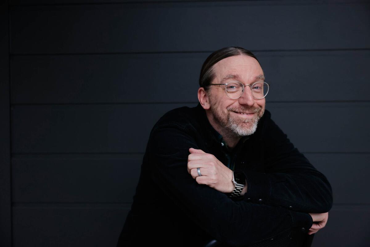 Screenwriter David Kajganich folds his arms and smiles for a portrait.