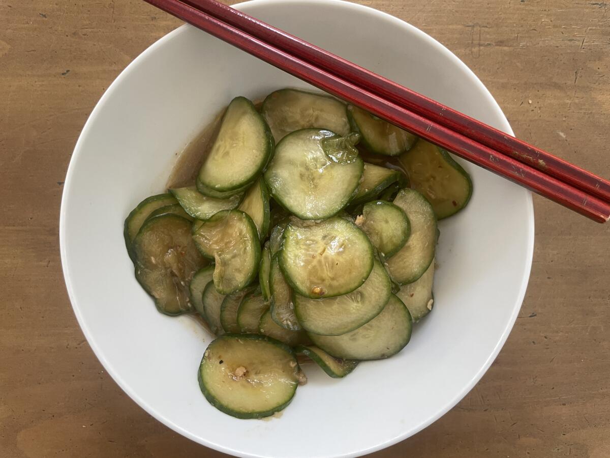 A cucumber salad in a bowl with chopsticks