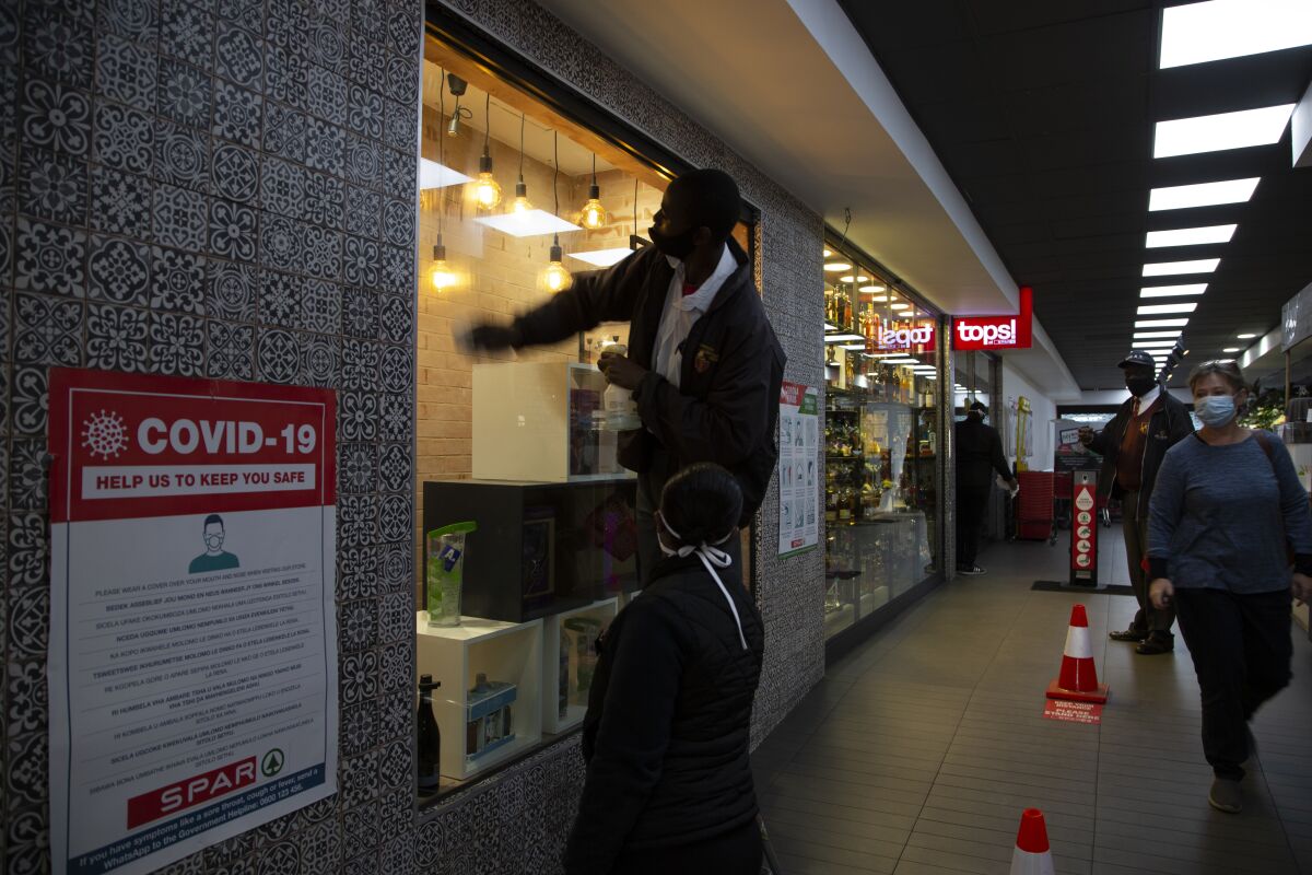 A man cleans a store window at a Johannesburg liquor store in Johannesburg Tuesday, Aug. 18, 2020 as the country lifted its coronavirus-linked ban on the sale of alcohol and tobacco products. The purchase of alcohol and cigarettes was banned when the country went into a strict nationwide lockdown on 27 March to stem the spread of coronavirus. (AP Photo/Denis Farrell)