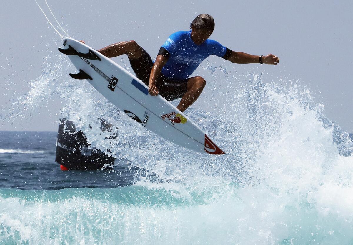 Kanoa Igarashi of Huntington Beach grabs his board as he gets air during the U.S. Open of Surfing men's semifinals on Sunday.