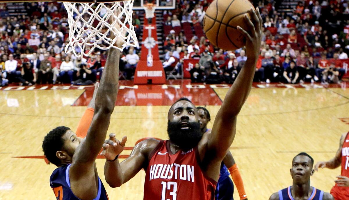 Rockets guard James Harden, right, drives past Thunder forward Paul George for a layup during the first half Tuesday.