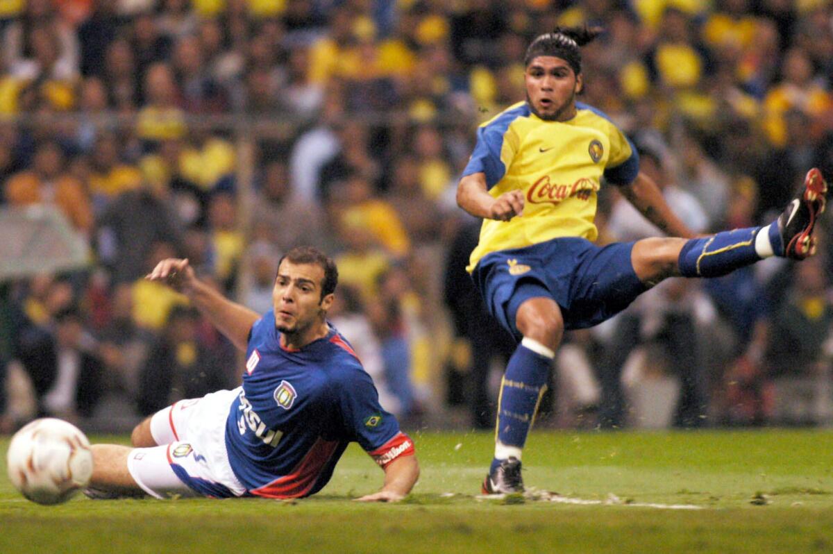 El delantero chileno Reinaldo Navia (der) del América de México, dispara y convierte en gol, sobre la defensa del equipo brasileño Sao Caetano durante el partido de vuelta de la Copa Libertadores de América.