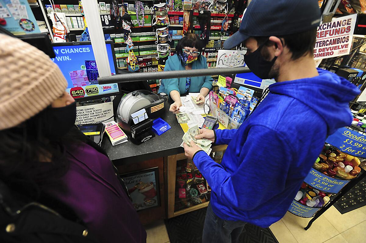Michael and Amanda Lazovich of Plain, Pa., purchase Powerball and Mega Millions lottery tickets at the Anthracite Newsstand on Public Square in Wilkes-Barre, Pa., Thursday, Jan. 14, 2021. The next Mega Millions drawing is Friday night, when an estimated $750 million prize will be up for grabs. The drawing for an estimated $640 million Powerball jackpot will be Saturday night. (Mark Moran/The Citizens' Voice via AP)