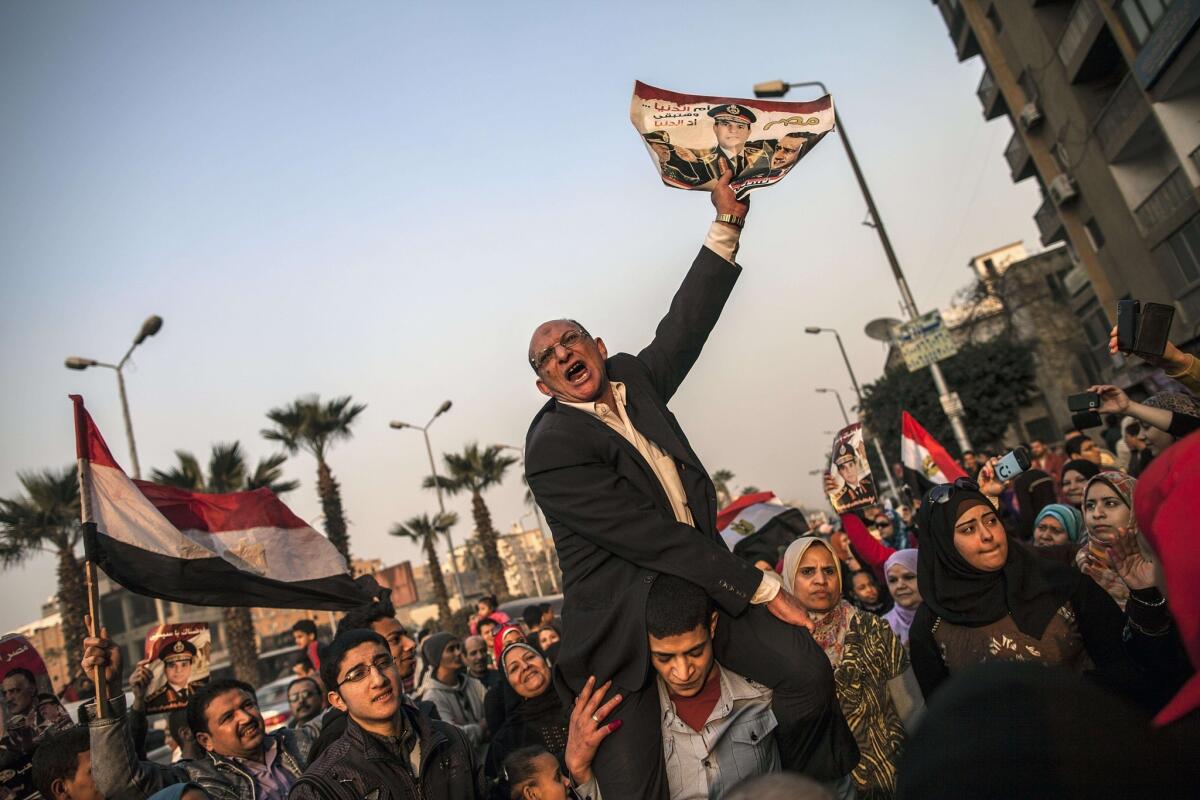 A man holds a picture of Egypt's army chief, Gen. Abdel Fattah Sisi, outside a polling station in Giza, where voting was taking place on a proposed constitution.