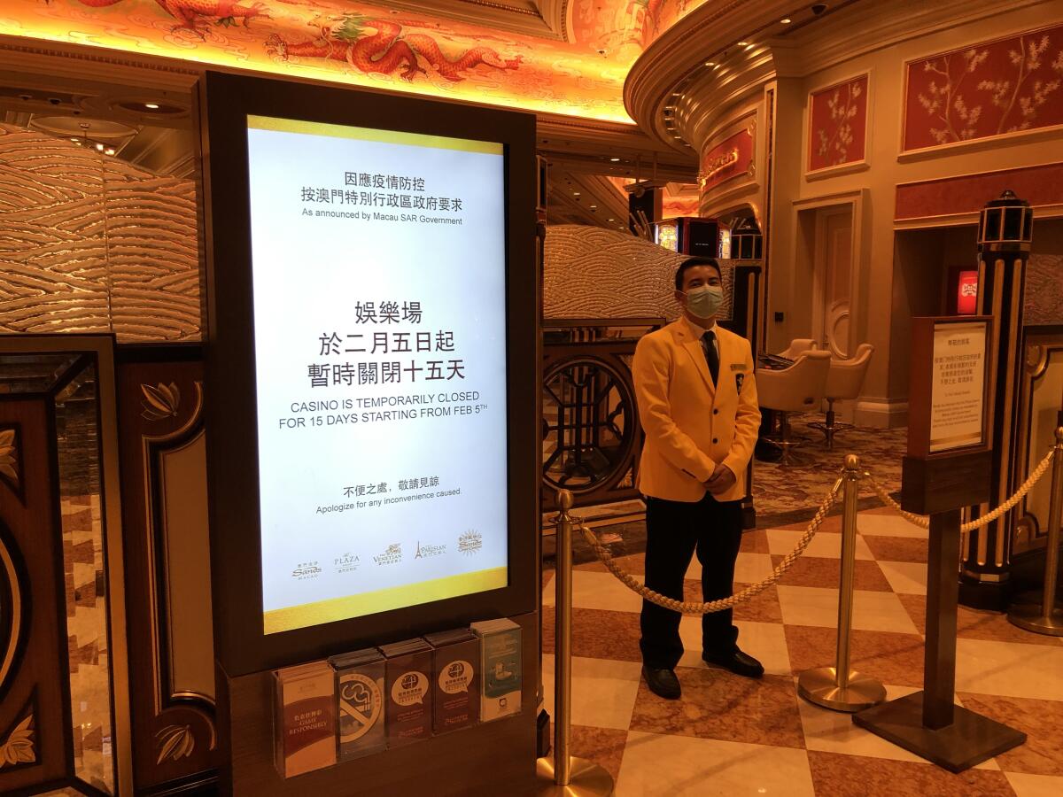 A security guard blocks the entrance to the Venetian Macao's gaming floor to comply with the territory's 15-day shutdown of casinos to stop the spread of the new strain of coronavirus.