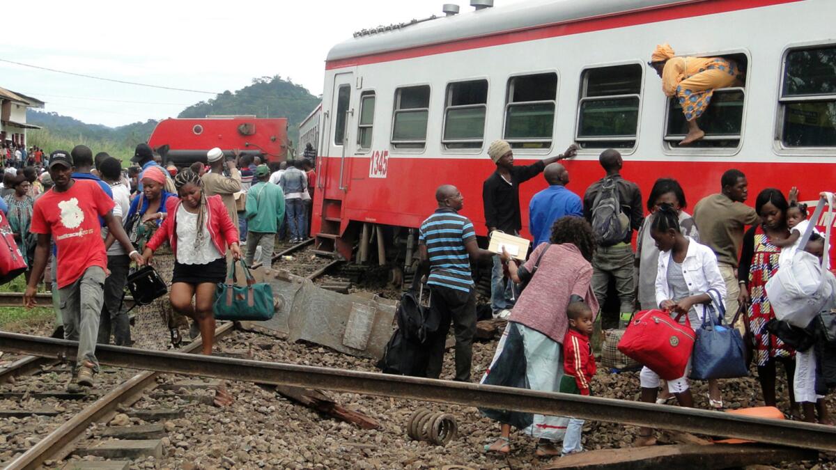 One passenger escapes a derailed car through a window as others make their way from the site of a train crash in Eseka, Cameroon, on Oct. 21, 2016.