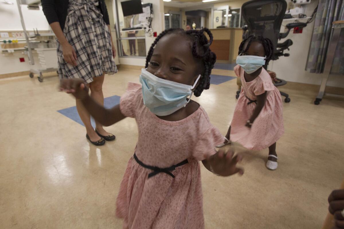 The 3 year-old Kiendrebego twins, Faith Juliet, foreground, and Grace Alice, rear, played with surgical masks in the San Diego Navy hospital's neonatal intensive care unit where they spent the first few months of their lives after they were born prematurely in 2013