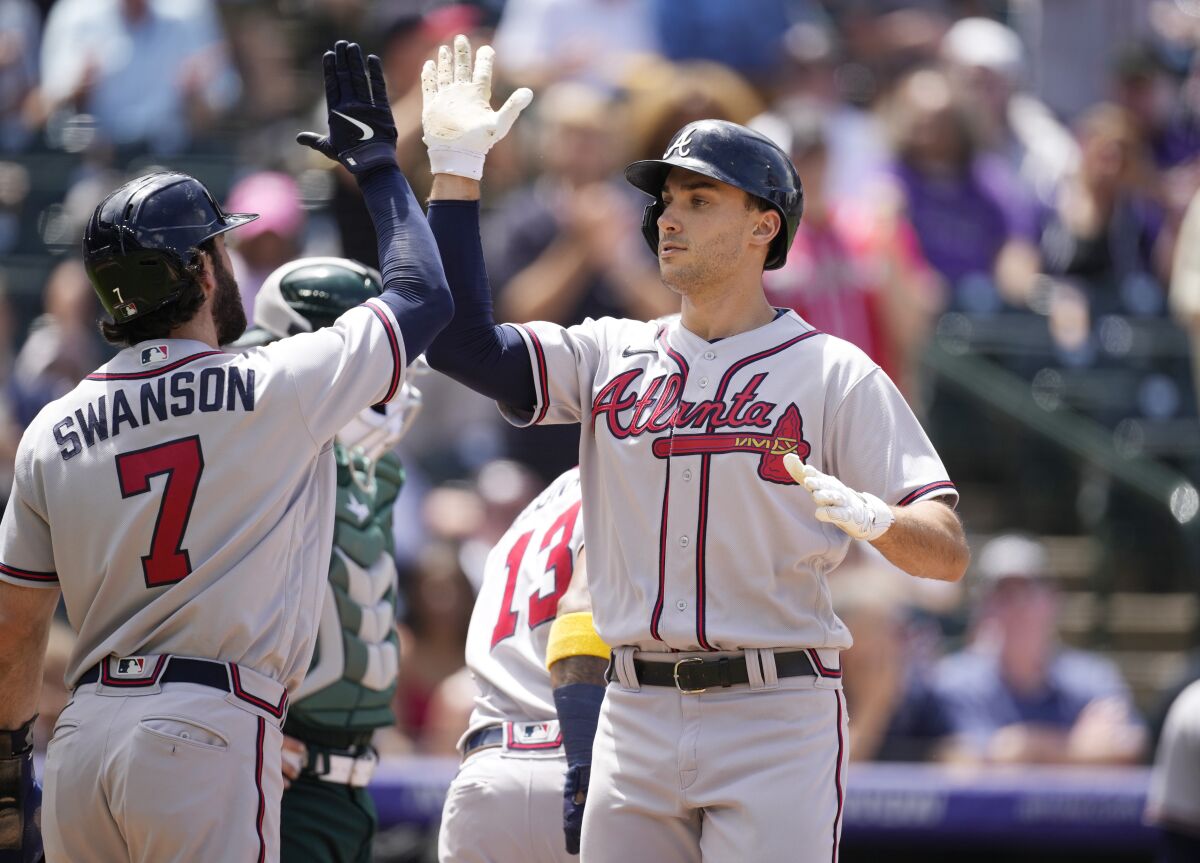 Atlanta Braves' Dansby Swanson, left, congratulates Matt Olson who crosses home plate after hitting a three-run home run off Colorado Rockies starting pitcher Ryan Feltner in the second inning of a baseball game Sunday, June 5, 2022, in Denver. (AP Photo/David Zalubowski)