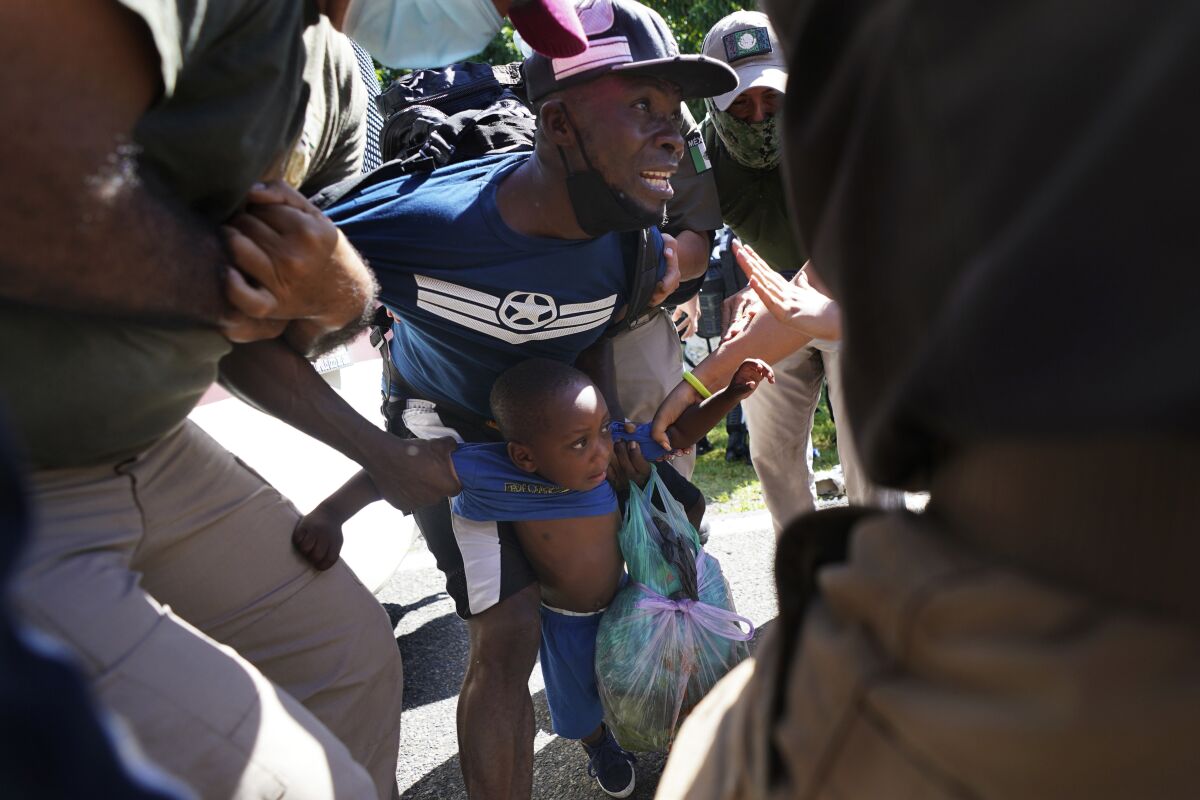 Immigration agents detains a Haitian migrant and his son as they walked along a highway in Escuintla, Chiapas state, Mexico, Thursday, Sept. 2, 2021. Mexico President Andres Manuel Lopez Obrador expressed frustration with a strategy of containing migrants in the south on Thursday and said he would write to U.S. President Joe Biden to insist that country contribute to his favorite development projects in the region. (AP Photo/Marco Ugarte)