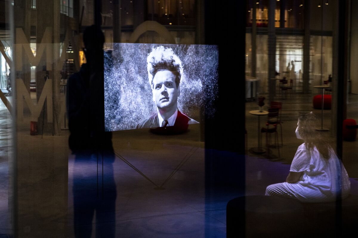 A viewer watches a scene from David Lynch's "Eraserhead" in a darkened gallery at the Academy Museum.