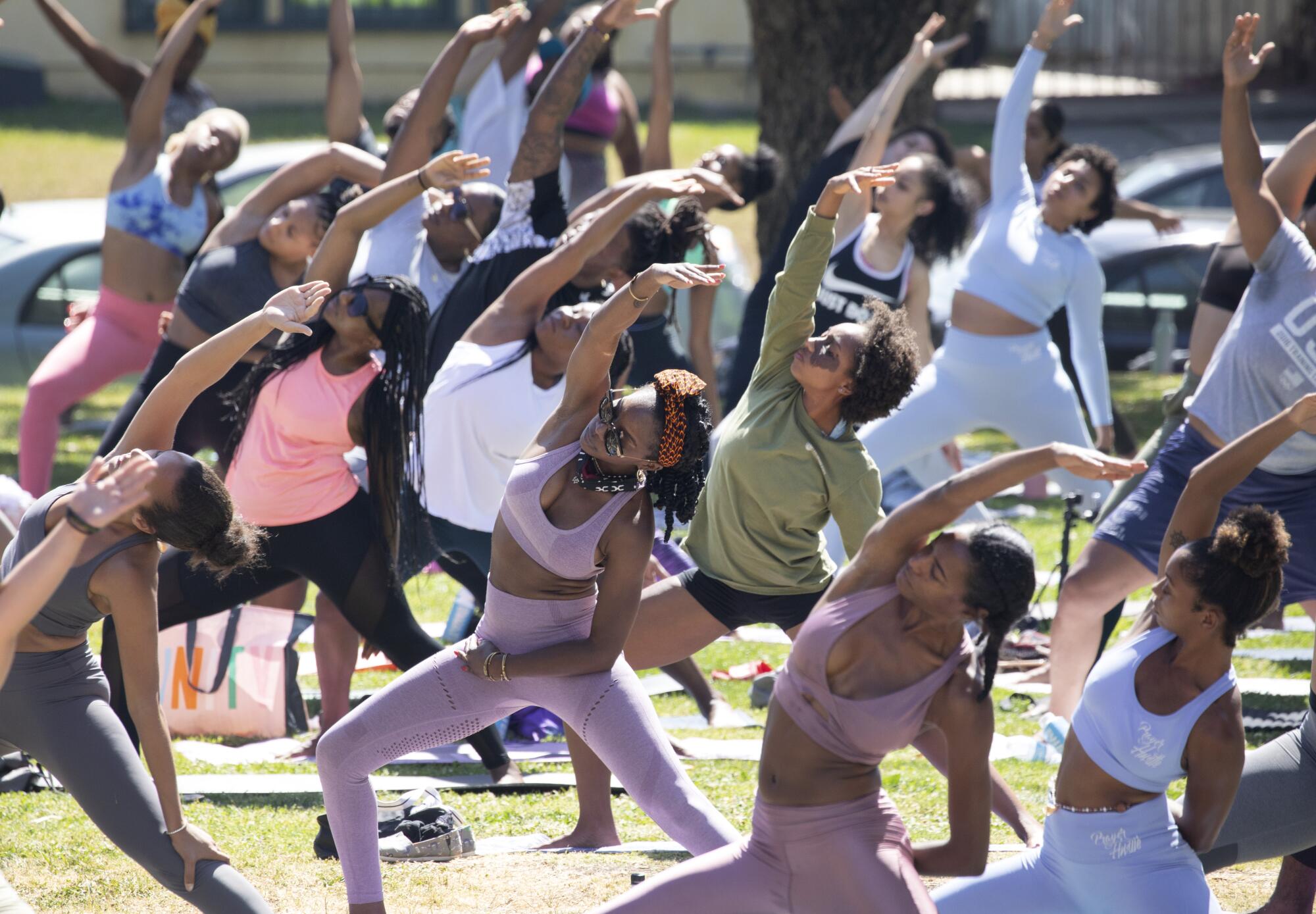 A group of people do yoga in a park.