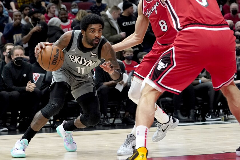 Brooklyn Nets' Kyrie Irving looks to drives past Chicago Bulls' Zach LaVine (8) and Nikola Vucevic during the first half of an NBA basketball game Wednesday, Jan. 12, 2022, in Chicago. (AP Photo/Charles Rex Arbogast)