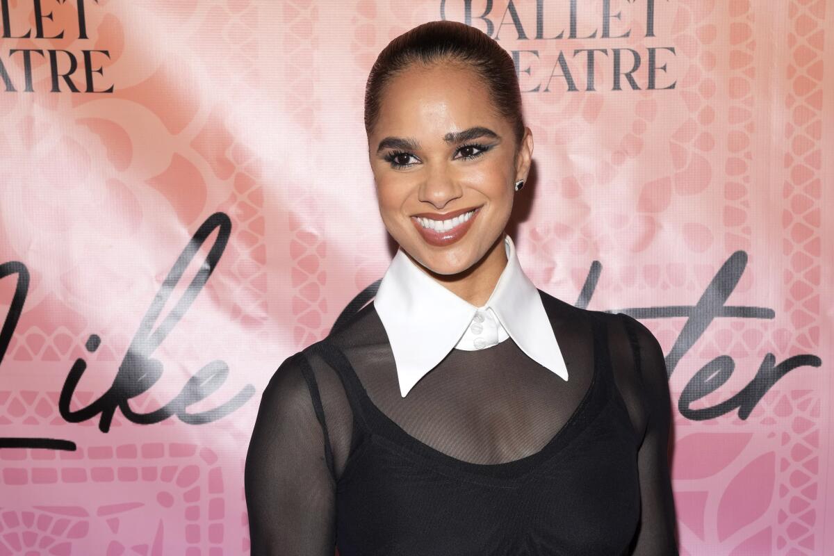 Misty Copeland with her hair slicked back in a sheer black dress with a large white collar