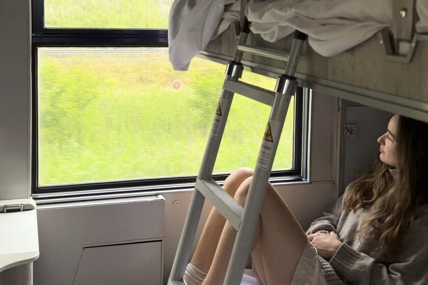 A young woman looks out at the Italian countryside on TrenItalia's Intercity Notte sleeper train from Palermo to Rome.