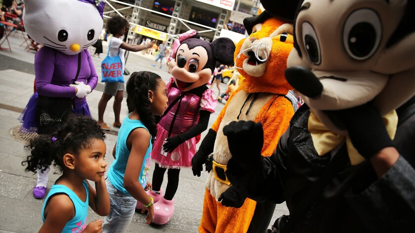 Costumed street performers wait to pose with tourists for tips in New York's Times Square in 2014.
