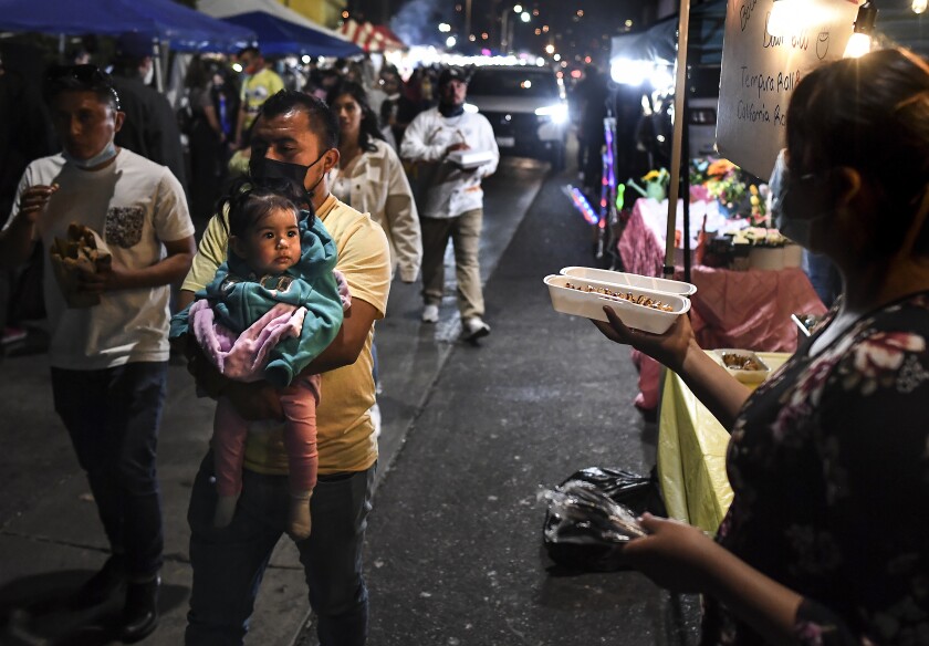 People walk by food stalls at Avenue 26 night market