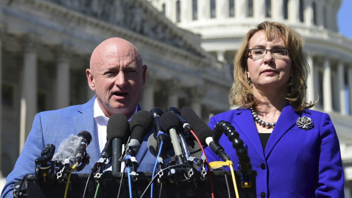 Former Rep. Gabrielle Giffords listens as her husband, Mark Kelly, speaks on Capitol Hill on Oct. 2, 2017.