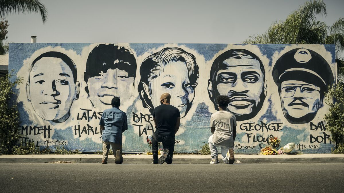 This image released by CBS shows Obba Babatund, portraying Daniel Harrison Sr., from left, Shemar Moore, portraying his son Hondo, and Deshae Frost, as Darryl, kneel in front of a mural in a scene from "S.W.A.T." In the episode titled, "3 Seventeen Year Olds," airing in the first hour of a two-hour season premiere episode on Nov. 11, the trio confront the history of racial tension in Los Angeles through flashbacks to the city in 1992 following the Rodney King verdict. (CBS via AP)