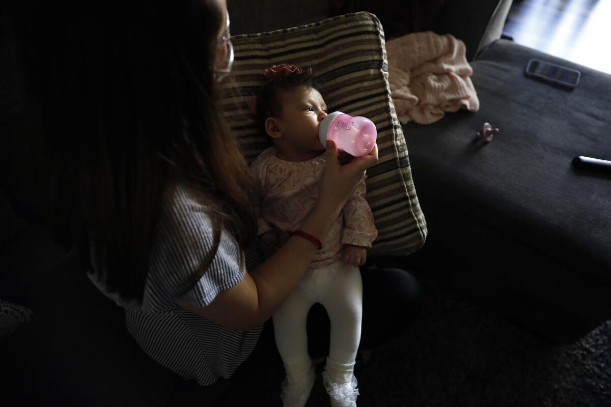 A mother bottle-feeds her daughter.