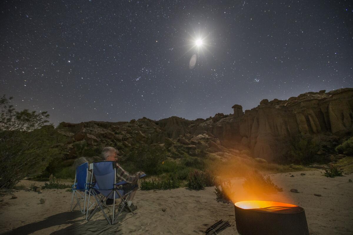 Charles and Julie Fleming check out the stars on a clear night by a campfire at dusk while camping in an Airstream Bambi Sport at Red Rock Canyon Ricardo campground. (Allen J. Schaben / Los Angeles Times)