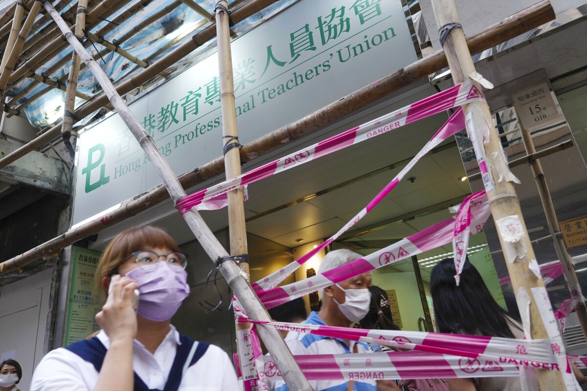 People walk past the entrance of the Hong Kong Professional Teachers' Union in Hong Kong, Tuesday, Aug. 10, 2021. The pro-democracy Professional Teachers' Union, the city's largest single-industry trade union comprising of 95,000 members, said it had disbanded as the "social and political environment has changed in recent years." (AP Photo/Vincent Yu)