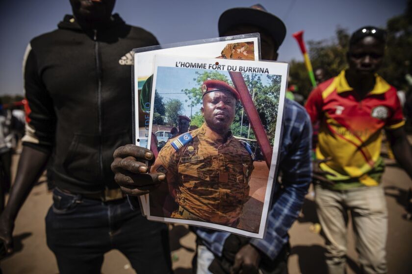 FILE - A man holds a portrait of Lt. Col. Paul Henri Sandaogo Damiba who has taken the reins of Burkina Faso, in Ouagadougou, Jan. 25, 2022. Attacks by Islamic extremists are on the rise five months after mutinous soldiers overthrew Burkina Faso's democratically elected president in January. And analysts say that could undermine support for Damiba's regime. Writing on portrait reads in French "The strong man of Burkina". (AP Photo/Sophie Garcia, File)