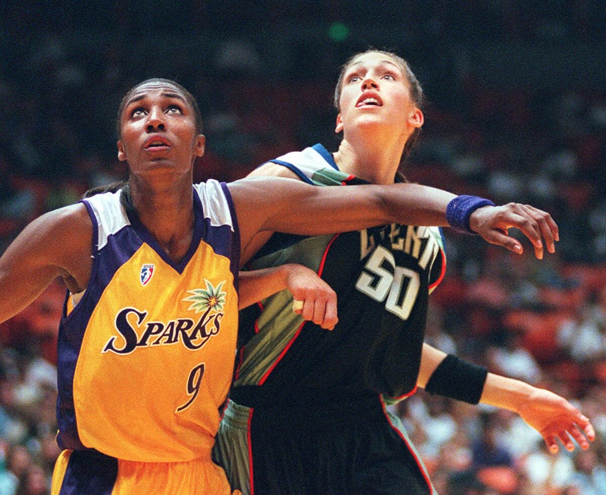 Two WNBA players battle for rebound position during a basketball game 