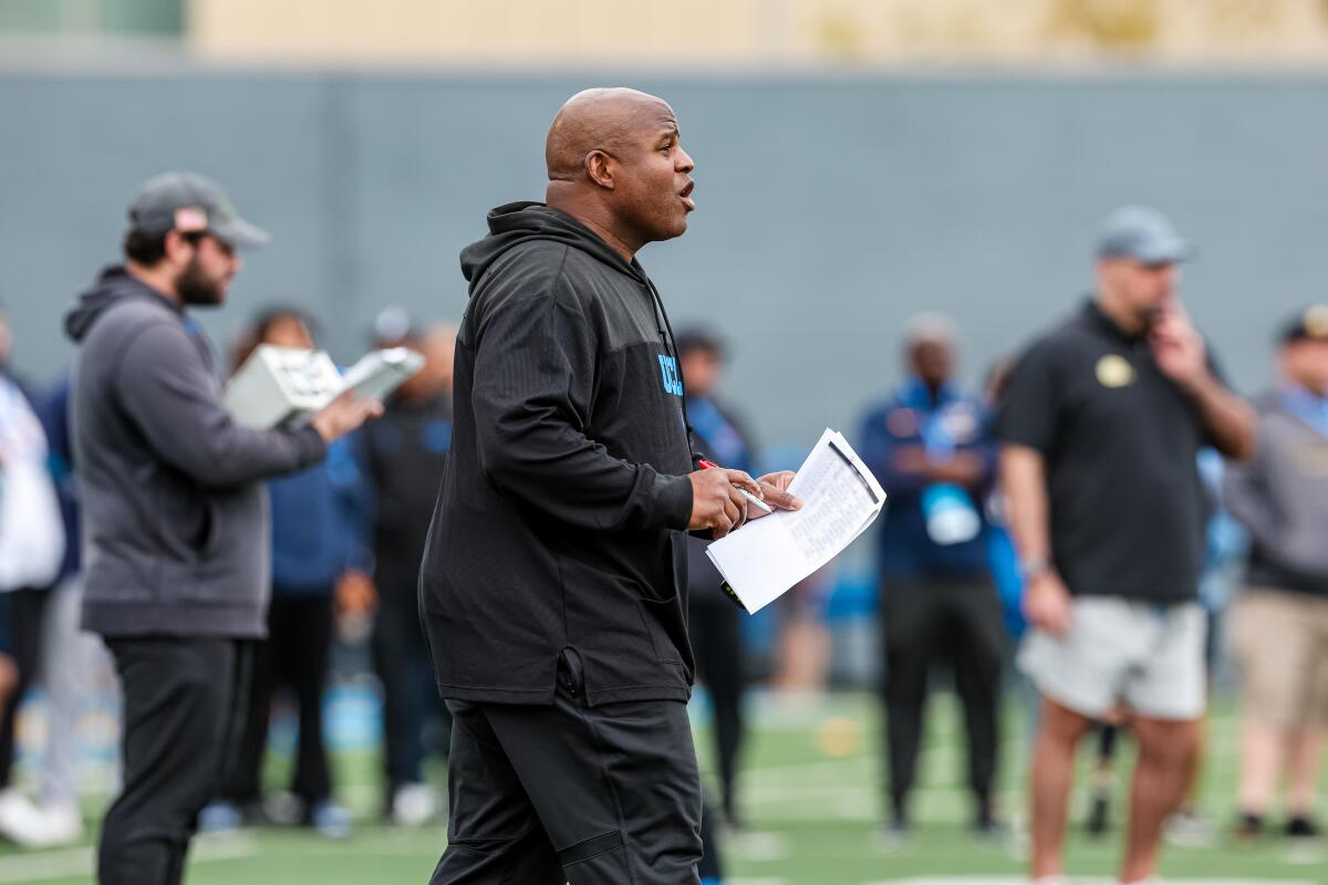 UCLA associate head coach and offensive coordinator Eric Bieniemy walks on the field during spring practice.