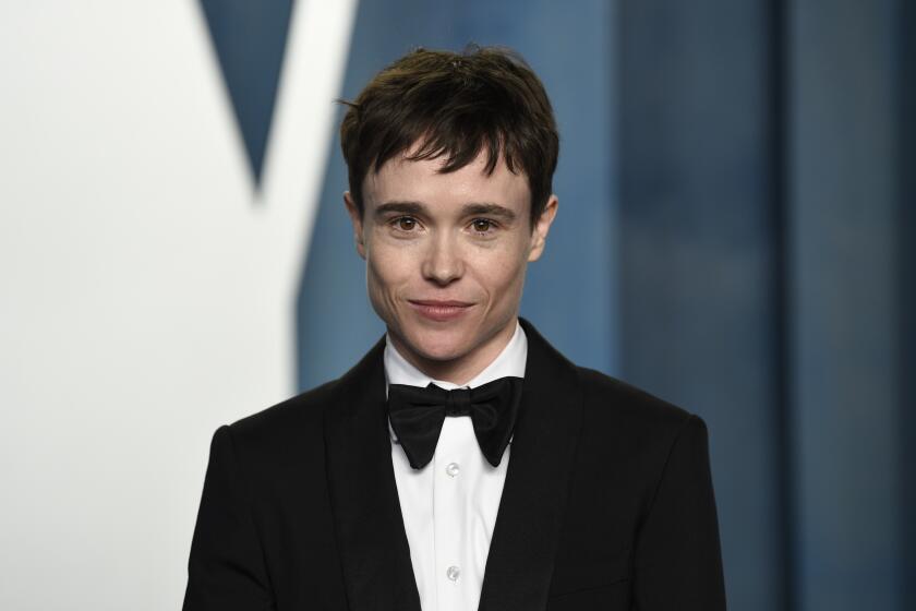 A person with short brown hair posing in a black tuxedo and bowtie