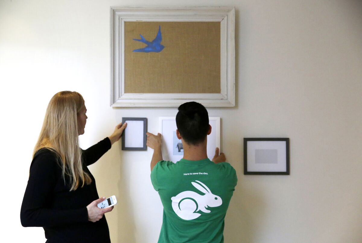 Taskrabbit tasker consults resident on the placement of frames while hanging picture frames in the baby's room.