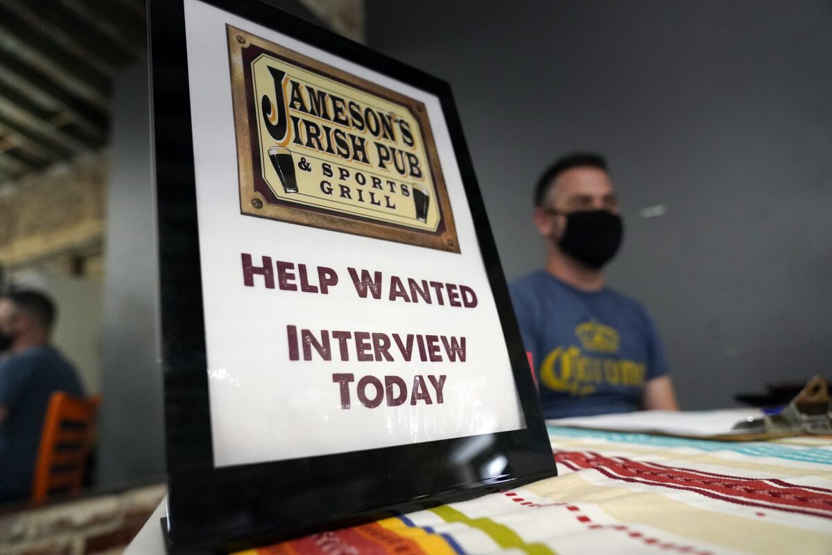 FILE - A hiring sign is shown at a booth for Jameson's Irish Pub during a job fair on Sept. 22, 2021, in the West Hollywood section of Los Angeles. California's unemployment rate has fallen to 5.4% after employers added a surprising 138,100 jobs in February. (AP Photo/Marcio Jose Sanchez, File)