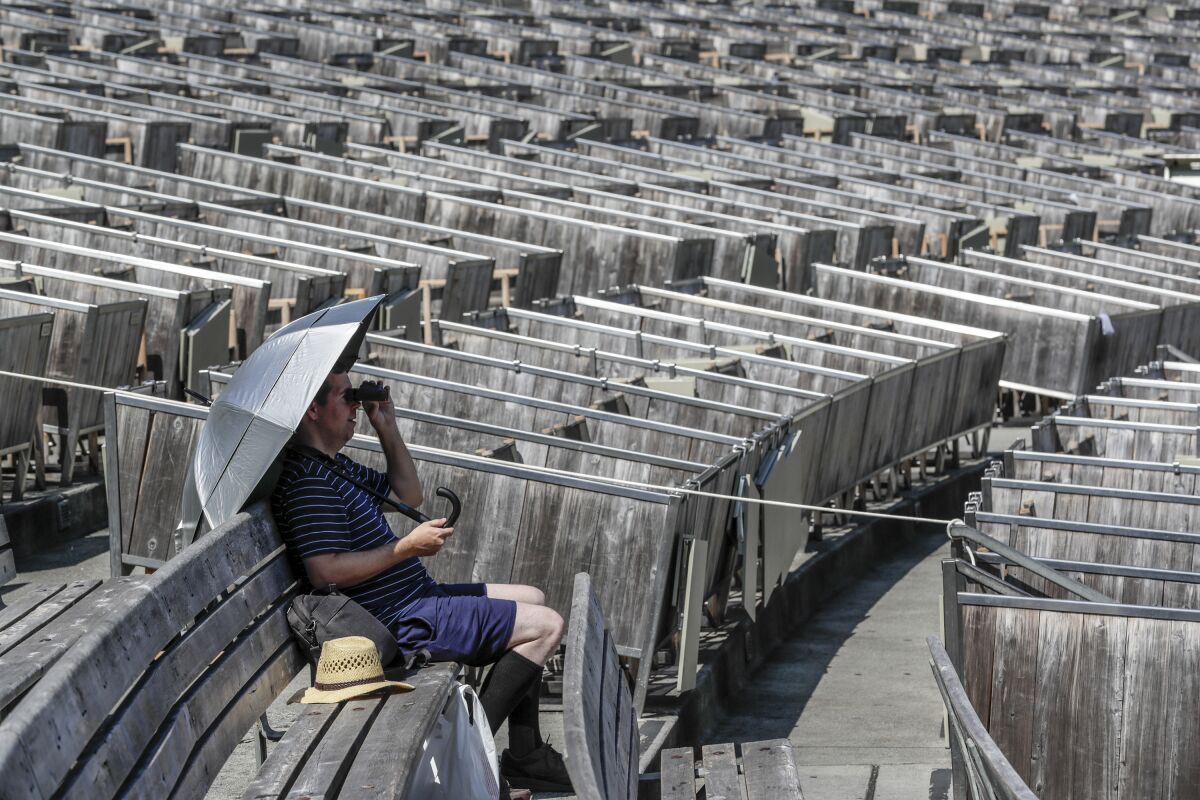 A person holds an umbrella while sitting in the empty seats of the Hollywood Bowl.