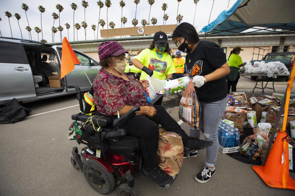 Beatriz Basurto gives food to Elvira Gavarie Urenda, 80, at a food giveaway in Oxnard on July 19.