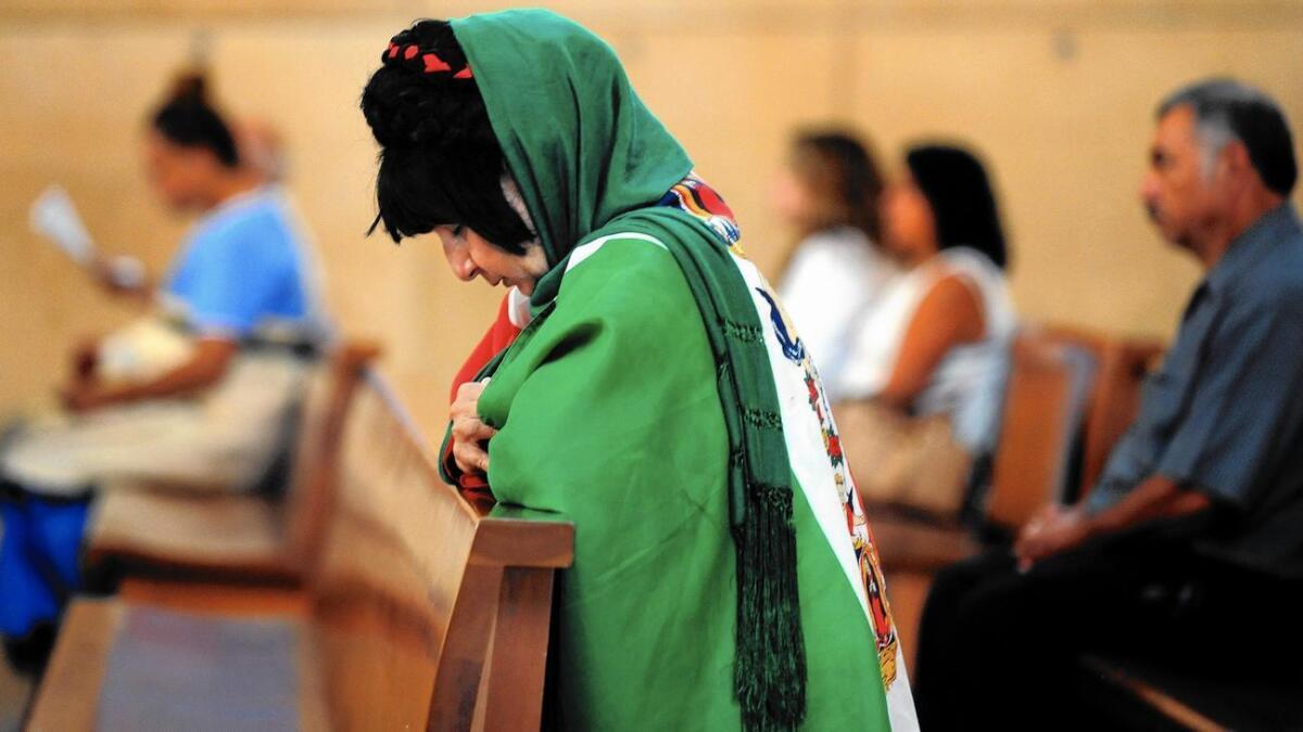 Una mujer cobijada por la bandera mexicana y la Virgen María ora en la Catedral de Nuestra Señora de Los Angeles en esta ciudad.