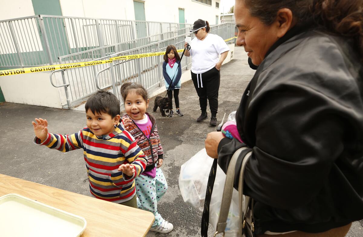 Noah Garcia and cousin Mia Porres pick up meals with their grandmother Zoila Umana from LAUSD volunteers 