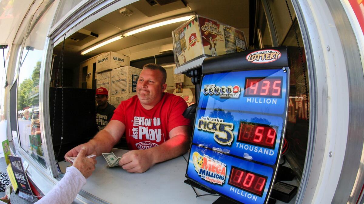 Chris Raff of Lincoln, Neb., hands a Powerball ticket to a customer in Omaha.